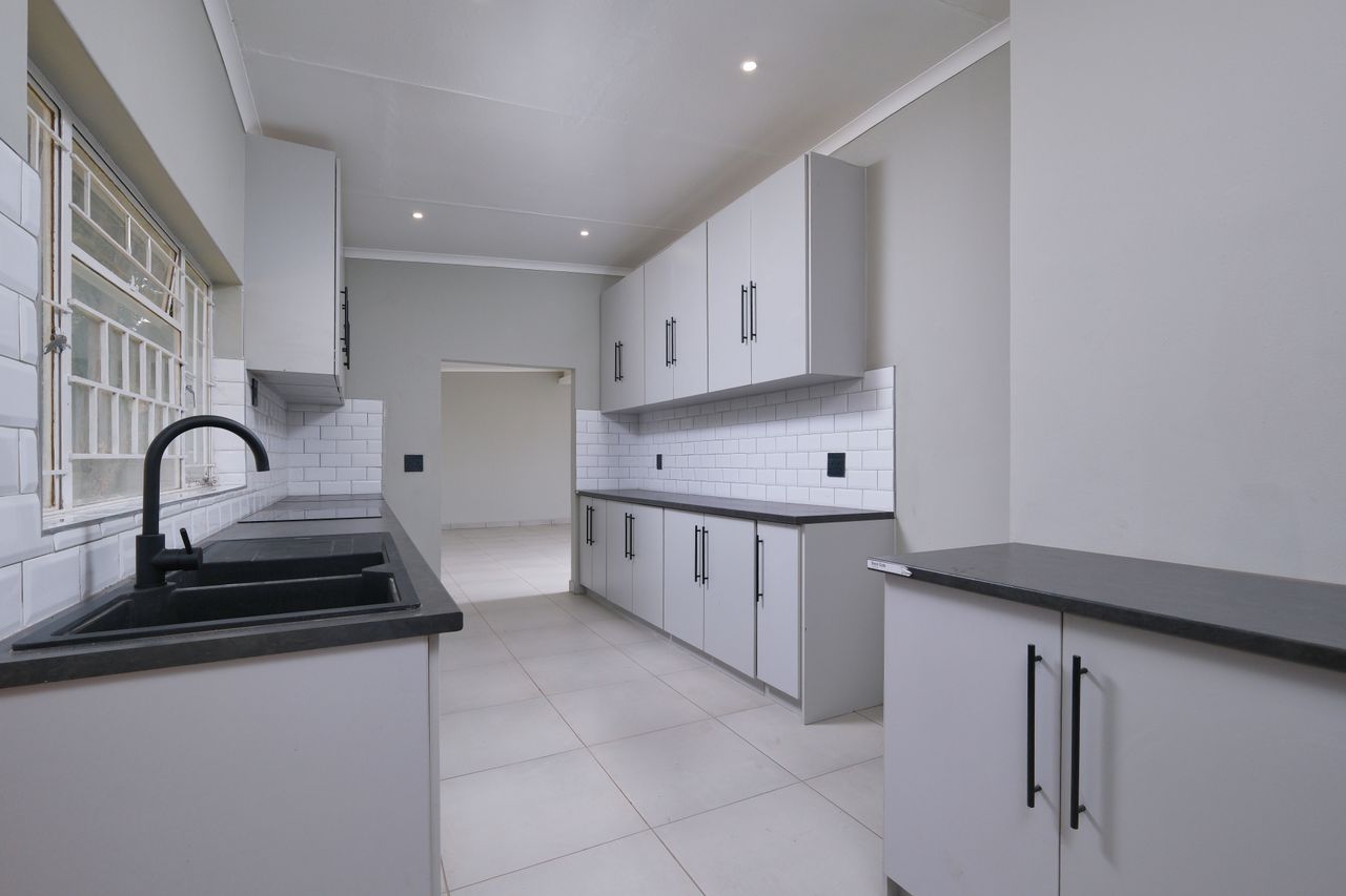Elegant modern kitchen with sleek design, featuring black appliances and white cabinetry in Pretoria.