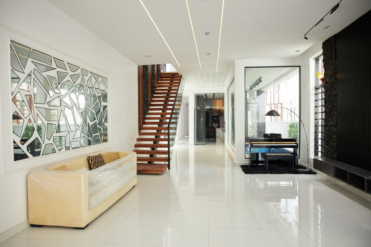 Bright modern interior with wooden staircase, geometric window design, and sleek furniture